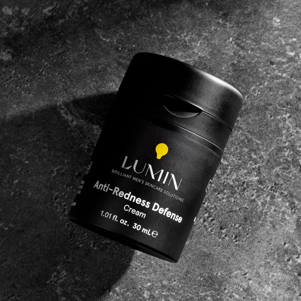 Lumin Anti-Redness Defense cream for men, 1.01 fl oz black skincare bottle on gray textured surface