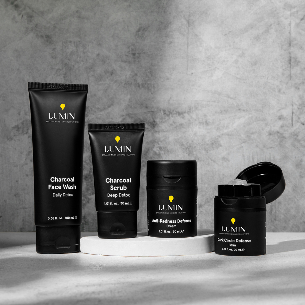 Men's skincare products set featuring Lumin charcoal face wash, charcoal scrub, anti-redness cream, and dark circle defense balm.