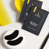 Lumin Bags-Be-Gone black eye patches with yellow comb and marble tray on white marble surface for men's skincare.