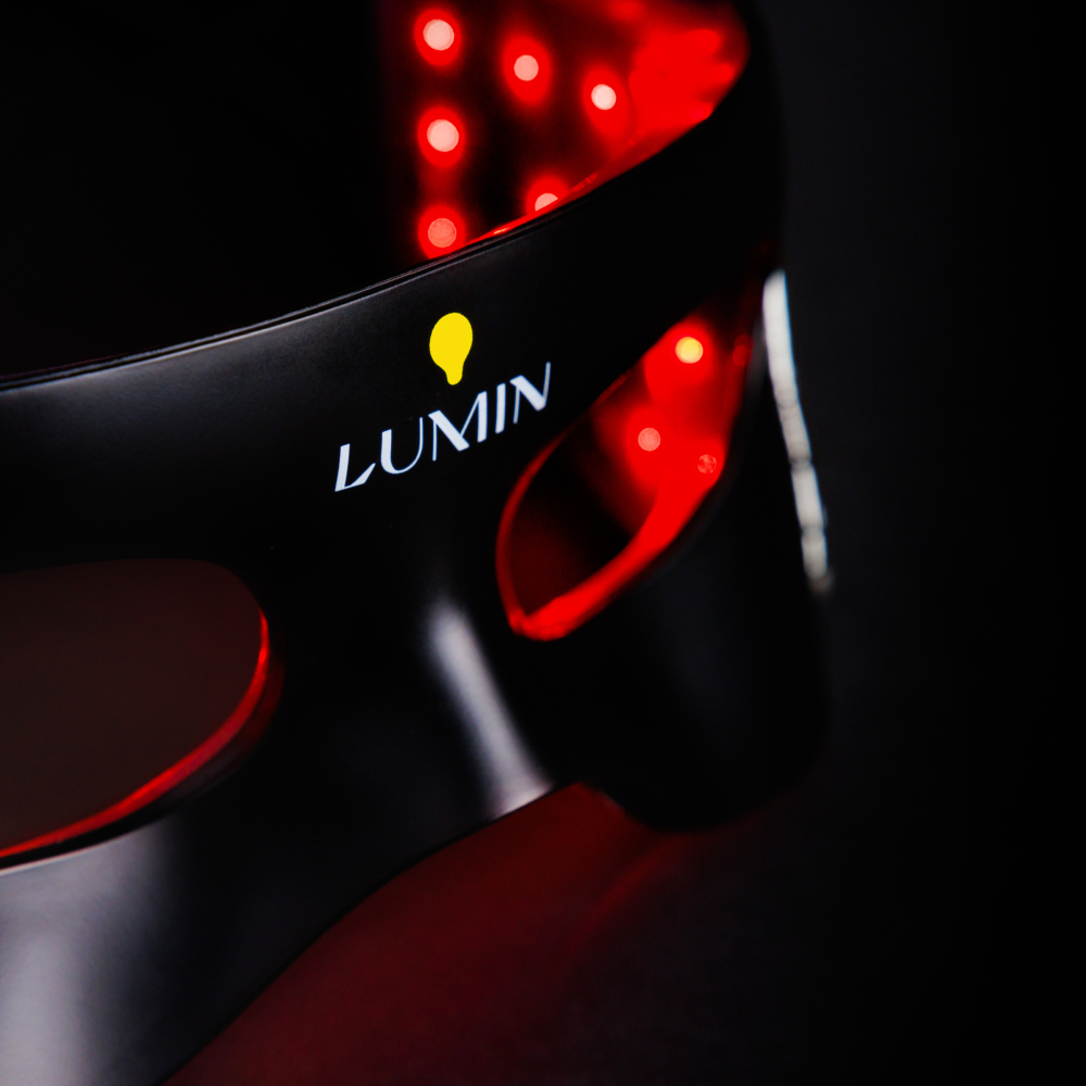 Black Lumin LED light therapy mask with red glowing LED bulbs for skin rejuvenation and anti-aging treatment.