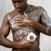 Muscular man washing chest with foamy soap bar under shower, skincare and personal hygiene concept.